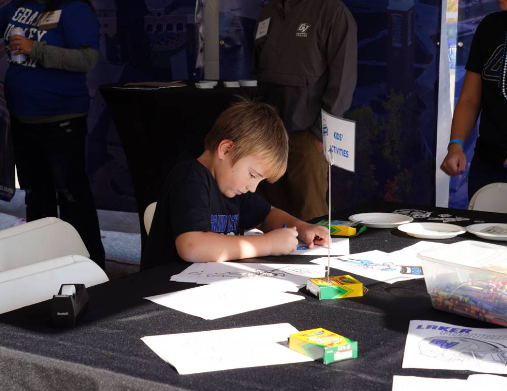 A kid coloring at the alumni tent.
